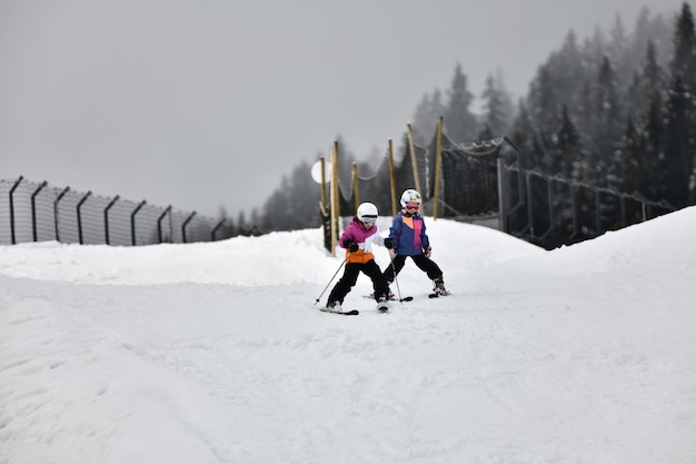 Zwei Kinder fahren im Schnee Ski mit einem Schild, auf dem Ski steht.