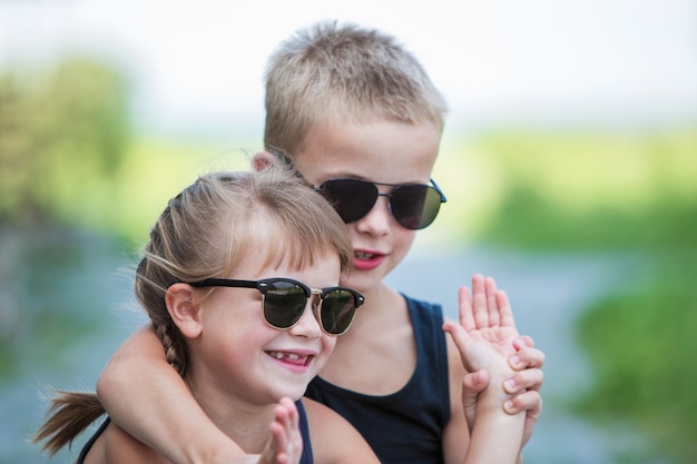 Zwei Kinder in der schwarzen Sonnenbrille, die Spaßzeit draußen im Sommer hat.