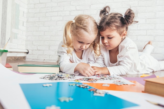 Zwei Kinder, kleine Mädchen im Vorschulalter, stellten das Puzzle auf den Boden