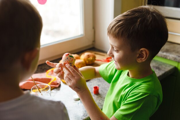 Zwei Kinder Ostern Vorbereitung durch Malen von Ostereiern und Feiertagsdekorationen zu Hause