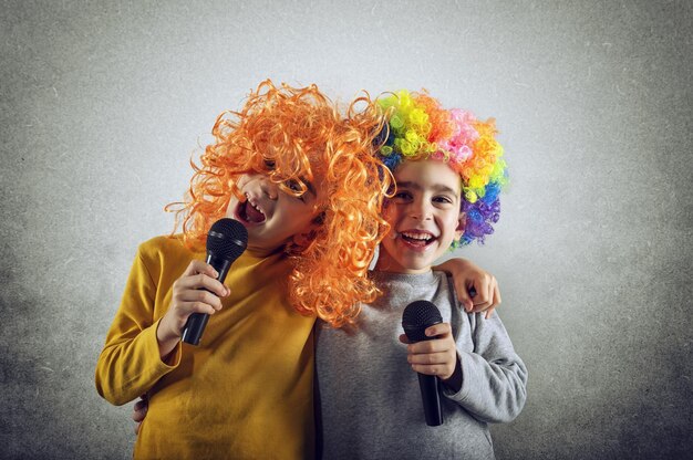 Zwei Kinder singen ein Lied mit Mikrofon und lustiger Perücke