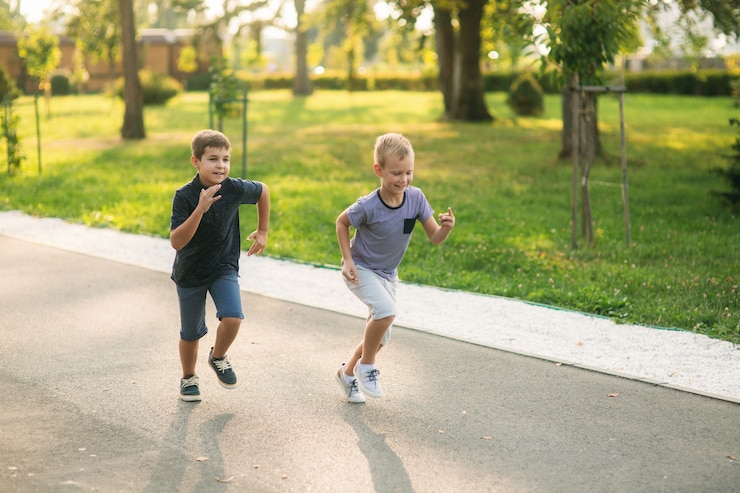 Foto zwei kinder spielen im park. zwei schöne jungs in t-shirts und shorts haben spaß beim lächeln