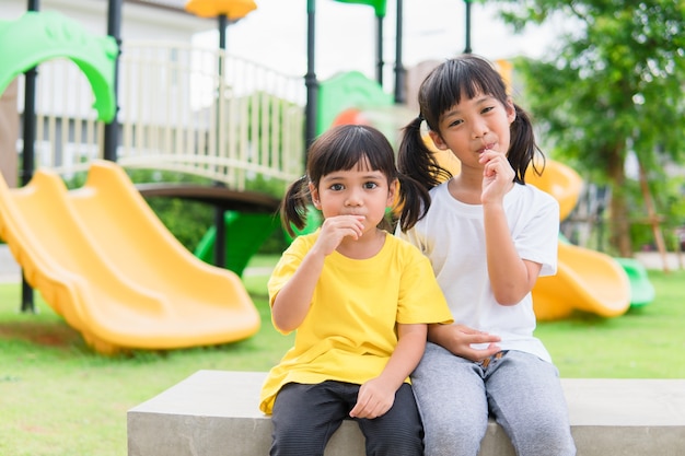 Zwei Kinder spielen und essen Lutscher auf dem Spielplatz