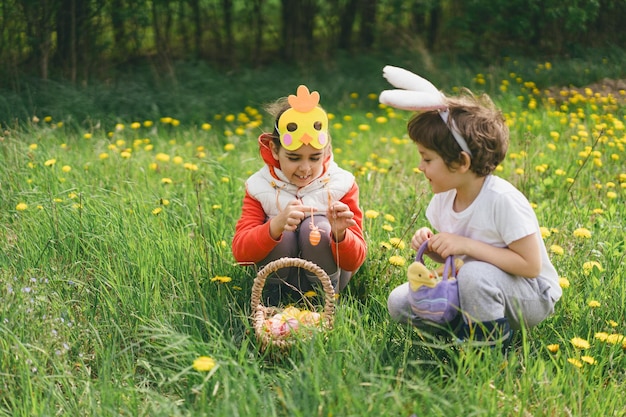 Zwei Kinder suchen in einem Frühlingsgarten nach Ostereiern.