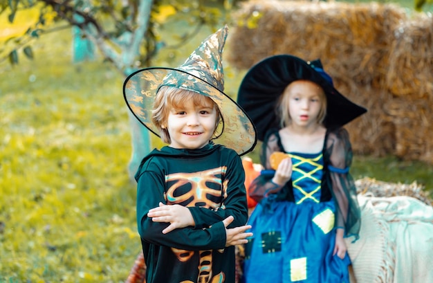 Zwei Kinder wie Skelett oder Hexe bereit für Trick or Treat überraschte Gruppe kleine Zombie im Halloween-Kostüm essen Leckerei Calaverita Süßigkeiten Kerzen