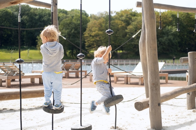 Zwei Kinderjungen Zwillingsbrüder, die an einem sonnigen Herbsttag auf dem Kinderspielplatz spielen