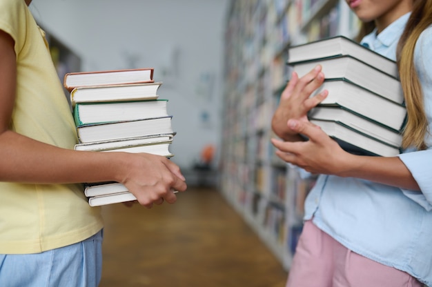 Zwei Klassenkameraden stehen zwischen Bücherregalen in einer öffentlichen Bibliothek