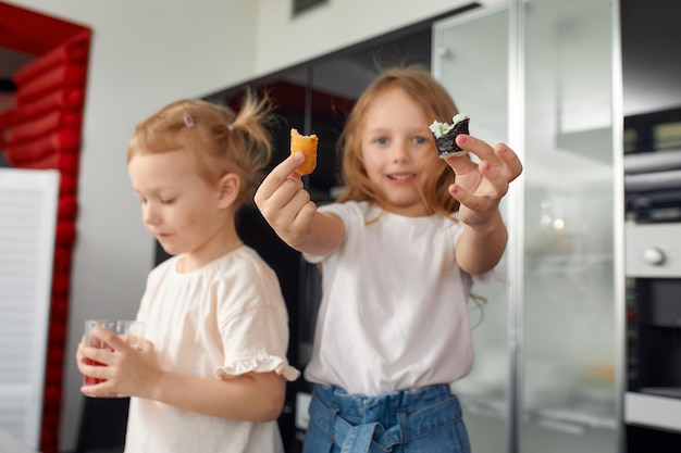 Zwei kleine Geschwister haben Spaß und essen zu Hause in der Küche mit japanischem Essen