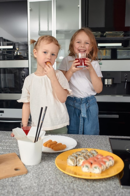 Zwei kleine Geschwister haben Spaß und essen zu Hause in der Küche mit japanischem Essen