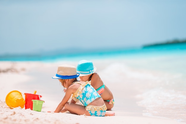 Zwei kleine glückliche Mädchen haben viel Spaß am tropischen Strand und spielen zusammen