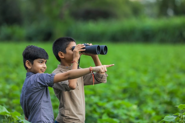Zwei kleine indische Jungen genießt in der Natur mit einem Fernglas