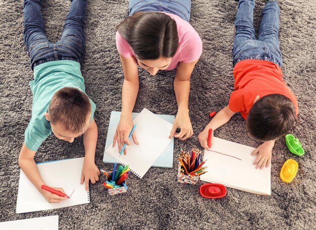 Foto zwei kleine jungen, die zu hause mit kindermädchen zeichnen