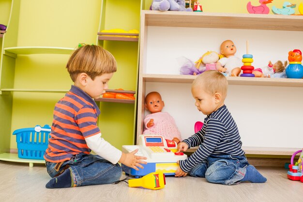 Zwei kleine Jungen spielen im Kindergarten die Rolle des Kassierers und Einkäufers