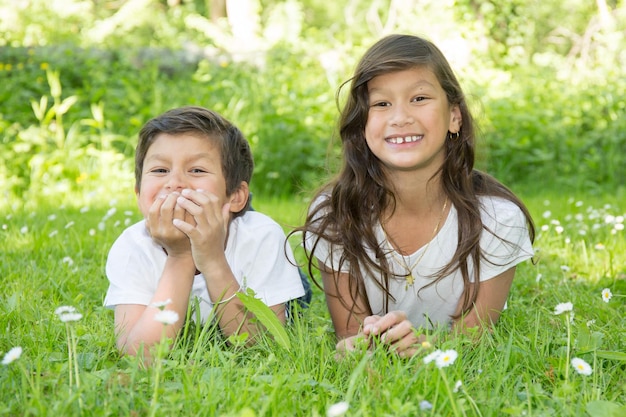 Zwei kleine Kinder in einem Parkmädchen und -jungen, die auf Gras liegen