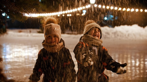 Zwei kleine Kinder stehen auf der Eisbahn und werfen Schnee in die Luft