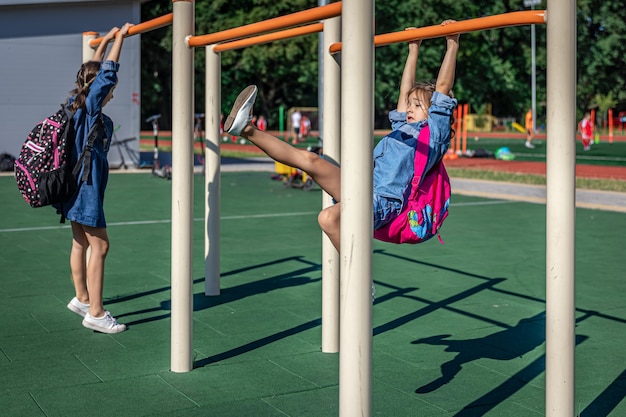 Zwei kleine Mädchen, Grundschüler, spielen nach der Schule auf dem Spielplatz.