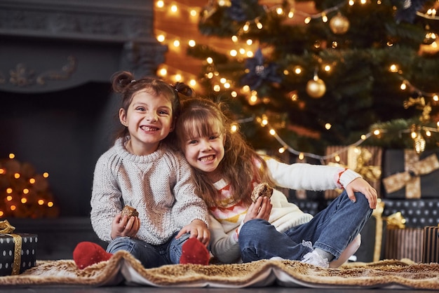 Zwei kleine Mädchen haben Spaß im weihnachtlich dekorierten Raum mit Geschenkboxen.