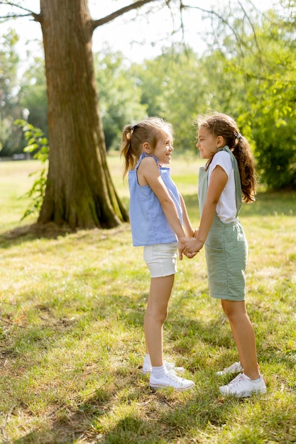 Zwei kleine Mädchen halten Händchen im Park