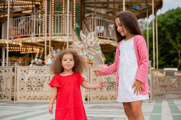 Zwei kleine Mädchen in einem Vergnügungspark, der Spielzeugbrise spielt