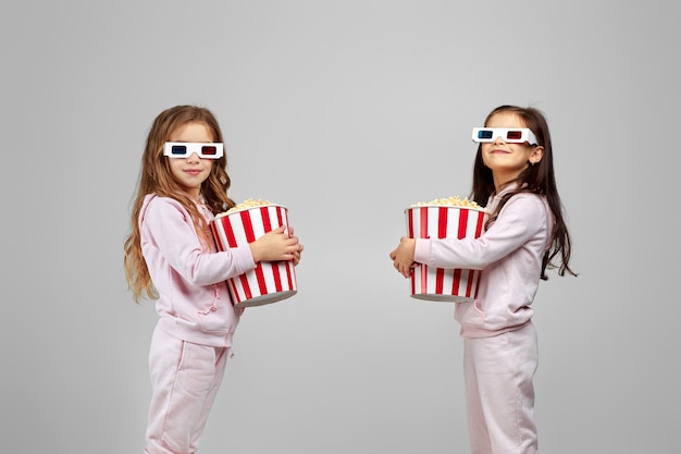 Zwei kleine Mädchen in rotblauen 3D-Brillen mit Popcorn-Eimern