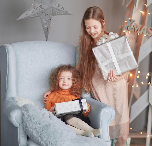 Zwei kleine Mädchen mit Weihnachtsgeschenken am Heiligabend