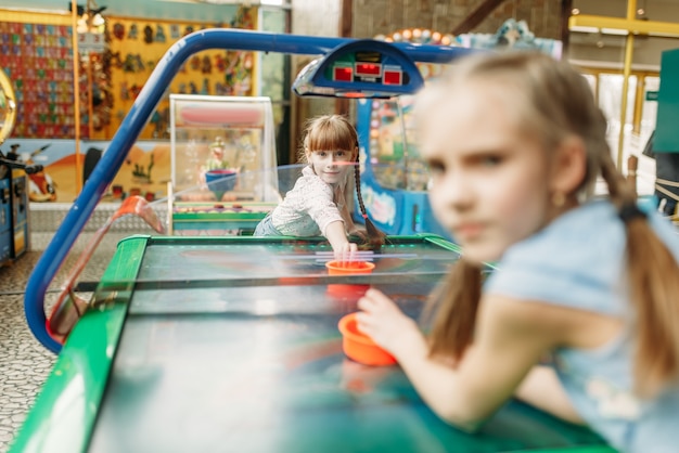 Zwei kleine mädchen spielen airhockey im spielzentrum