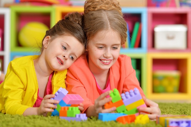 Zwei kleine Mädchen spielen mit bunten Plastikblöcken