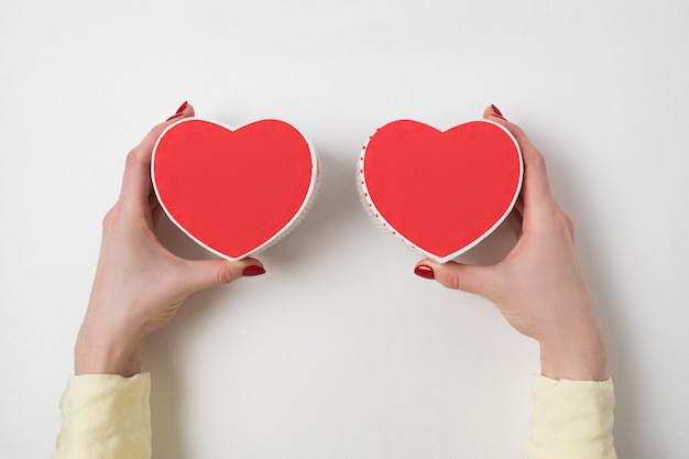 Zwei kleine rote Herzen formten Kästen auf weiblichen Händen an. Geschenk zum Valentinstag