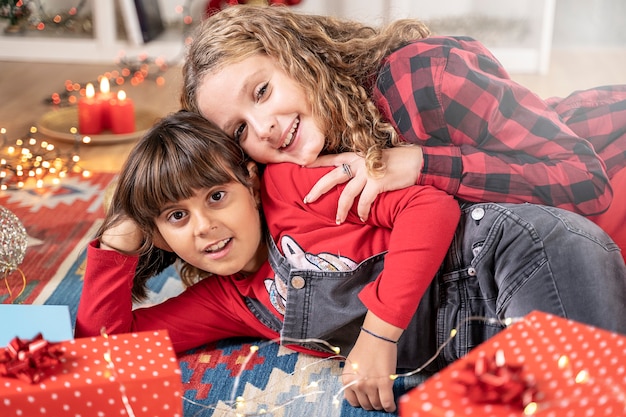 Zwei kleine Schwestern, die mit Geschenkbox in Weihnachtsatmosphäre spielen