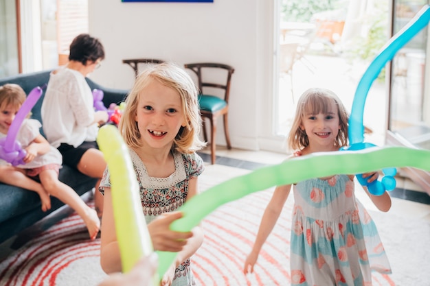 Zwei kleine Schwestern, die zu Hause mit dem Ballon spielen, der Spaß beim Lächeln hat