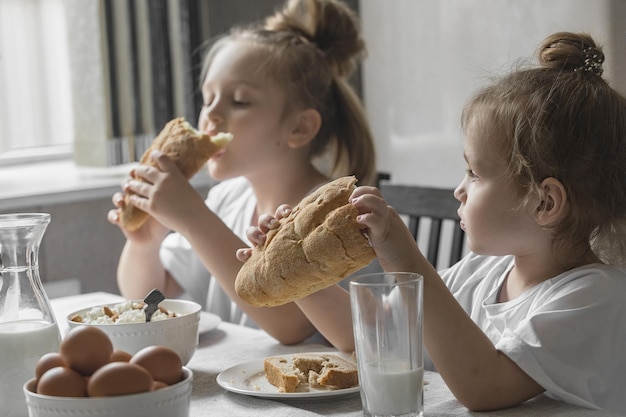 Zwei kleine Schwestern frühstücken zu Hause mit Naturprodukten