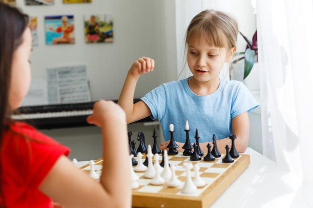 Zwei kleine Schwestern spielen zu Hause Schach