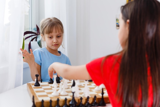 Zwei kleine Schwestern spielen zu Hause Schach