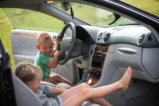 Zwei kleine süße Kinder, ein Bruder und eine Schwester, spielen im Auto am Steuer