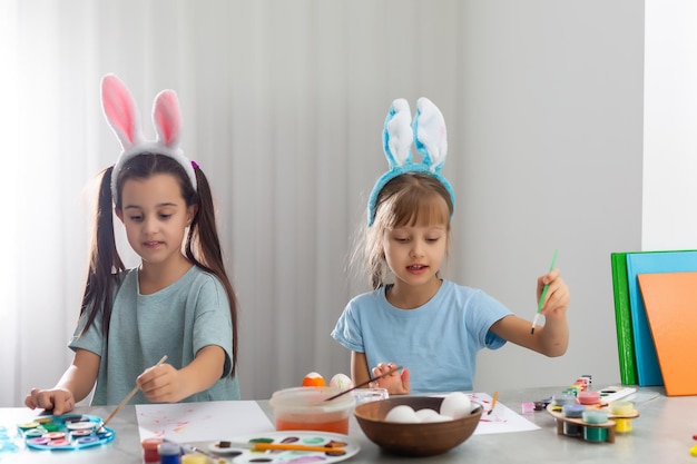 Zwei kleine süße Mädchen, die auf Ostereiern malen