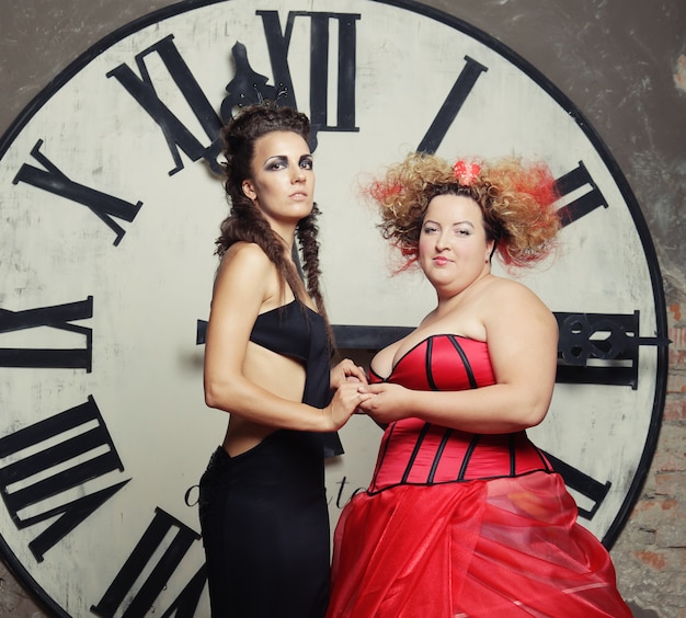 Zwei Königinnen posieren neben der Uhr.