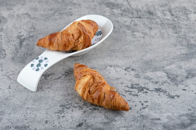 Zwei köstliche frische Croissantgebäckstücke auf Steinoberfläche.