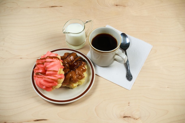 Zwei köstliche gezuckerte Donuts, serviert auf einem weißen Teller mit einer Tasse heißem Getränk an der Seite.