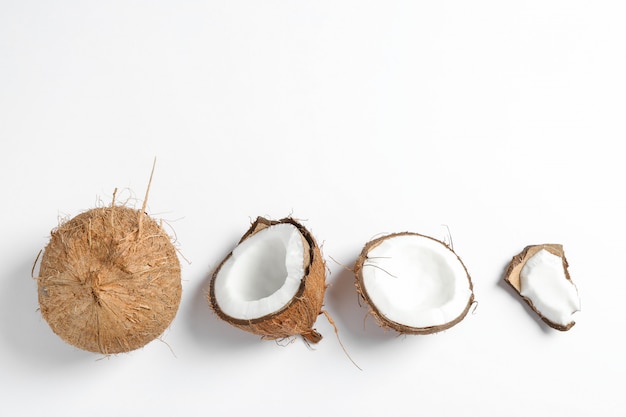 Zwei Kokosnüsse, von denen eine auf Weiß gespalten ist