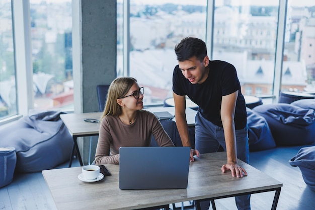 Zwei Kollegen besprechen die Arbeit an einem Laptop Freundliche Beziehungen im Büro zwischen Kollegen Workflow im Büro