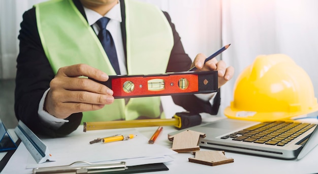 Zwei Kollegen diskutieren über Datenarbeit und Tablet-Laptop mit einem Architekturprojekt auf der Baustelle am Schreibtisch im Büro