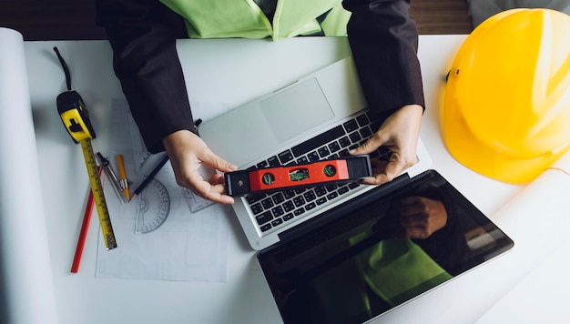 Zwei Kollegen diskutieren über Datenarbeit und Tablet-Laptop mit einem Architekturprojekt auf der Baustelle am Schreibtisch im Büro