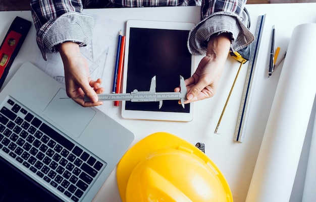 Zwei Kollegen diskutieren über Datenarbeit und Tablet-Laptop mit einem Architekturprojekt auf der Baustelle am Schreibtisch im Büro