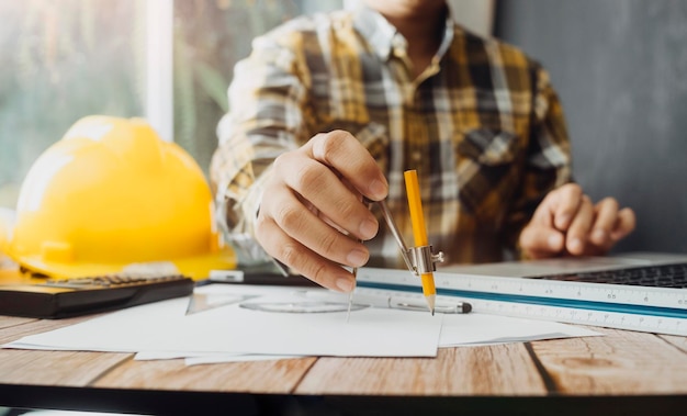 Zwei Kollegen diskutieren über Datenarbeit und Tablet-Laptop mit einem Architekturprojekt auf der Baustelle am Schreibtisch im Büro