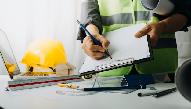 Zwei Kollegen diskutieren über Datenarbeit und Tablet-Laptop mit einem Architekturprojekt auf der Baustelle am Schreibtisch im Büro