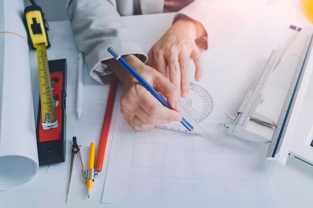 Zwei Kollegen diskutieren über Datenarbeit und Tablet-Laptop mit einem Architekturprojekt auf der Baustelle am Schreibtisch im Büro