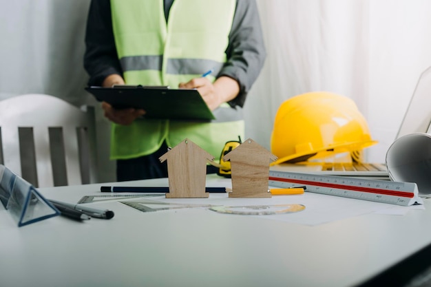 Zwei Kollegen diskutieren über Datenarbeit und Tablet-Laptop mit einem Architekturprojekt auf der Baustelle am Schreibtisch im Büro