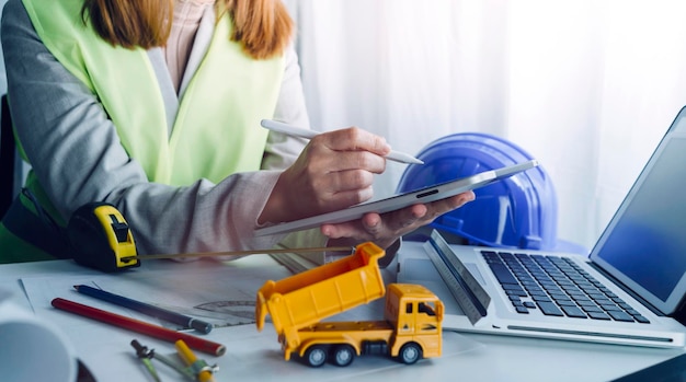 Zwei Kollegen diskutieren über Datenarbeit und Tablet-Laptop mit einem Architekturprojekt auf der Baustelle am Schreibtisch im Büro