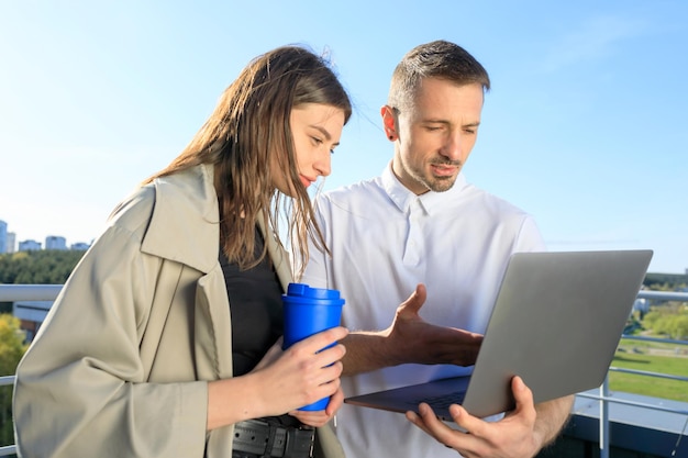 Zwei Kollegen mit Laptop auf dem Dach besprechen ein neues Bauprojekt