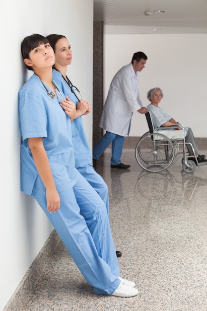 Foto zwei krankenschwestern, die auf wand sich lehnen